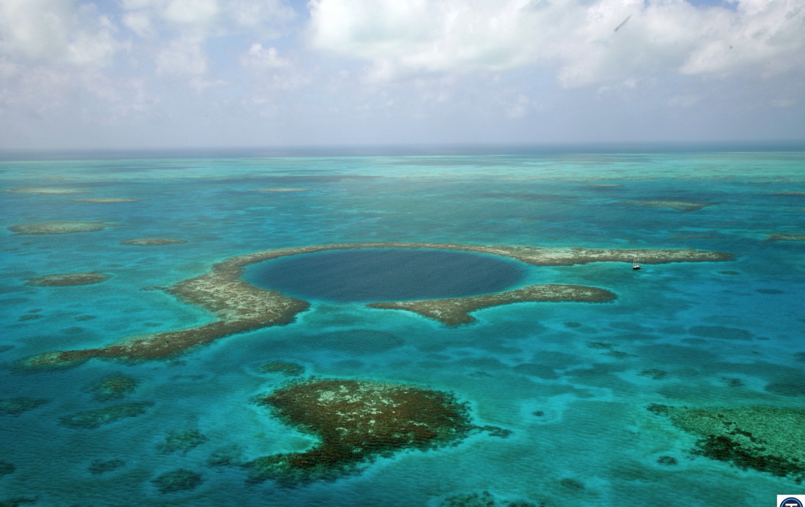 Aerial view of the Great Blue Hole, a deep circular sinkhole ringed by pale reef
